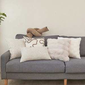 Modern lamb wool decorative pillow covers in neutral tones displayed on a sofa