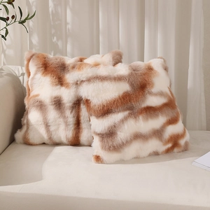 Pair of soft faux fur pillow covers with brown tie-dye stripes on a cozy sofa set