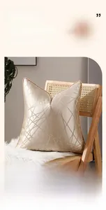 Vue détaillée de la housse de coussin en satin doré avec broderie géométrique sur un fauteuil