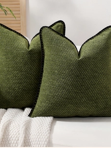 Close-up of forest green chenille cushion cover with black lace trim on knit blanket