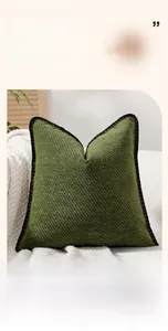 Detail of green chenille pillow cover with textured diagonal stripes and black wavy edge
