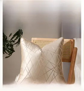 Détail de la housse de coussin jacquard doré champagne aux motifs géométriques sur une chaise