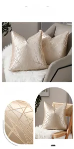 Détail macro de la housse de coussin en satin doré avec broderie géométrique chic