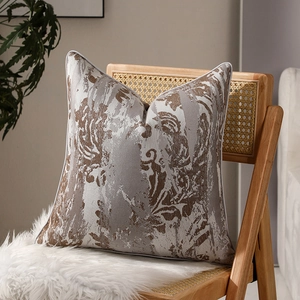 Housse de coussin luxe motif marbre avec passepoil blanc sur une chaise en rotin