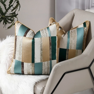 Paire de housses de coussin géométriques de luxe avec passepoil doré sur canapé
