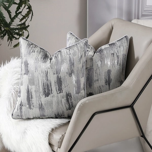 Lot de deux housses de coussin géométriques gris et argent avec passepoil sur chaise moderne