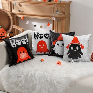 Set of four Halloween sequin ghost pillows on a white plush sofa with a cozy fireplace