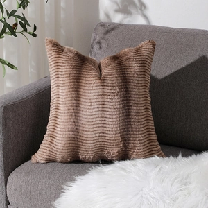Federa per cuscino in peluche marrone a righe su divano grigio in ambiente accogliente