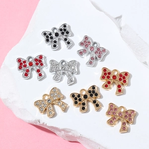 Colorful rhinestone bow charms for DIY jewelry making displayed on a white decorative stone