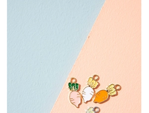 Macro detail of carrot alloy enamel charms in pink, white, and orange for DIY jewelry making