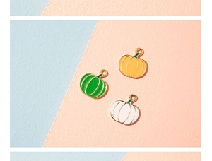 Détail de pendentifs citrouille en émail orange, blanc et vert pour bijoux DIY