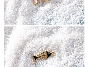 Macro detail of cartoon fish bone enamel charms in black and pink for DIY jewelry