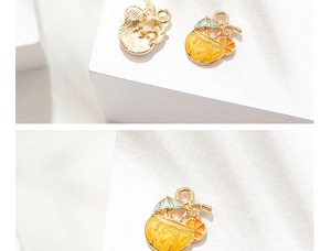Detalle de dije de cóctel tropical con copa naranja, sombrilla azul y acabado dorado