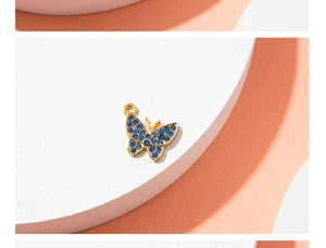 Macro shot of gold butterfly pendant with sparkling blue rhinestones on a white stand