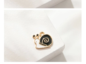 Macro detail of a cute cartoon snail alloy pendant with black and white enamel finish