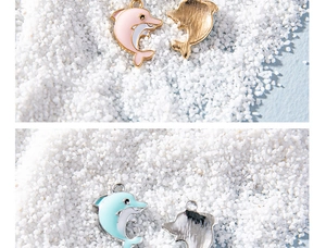 Macro detail of pink and blue enamel dolphin pendants with gold and silver bases