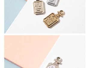Detailed macro view of gold and silver perfume bottle pendants with floral relief