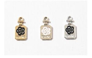 Macro detail of three alloy perfume bottle charms with camellia motif and engraving