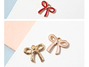 Macro view of bow pendant charms with colorful enamel finish and gold metal loops