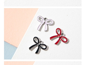 Close-up of bow knot alloy pendants in pink, red, and black for DIY jewelry crafts
