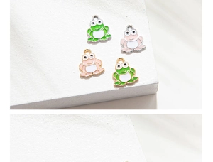 Detailed macro shot of green and pink cartoon frog alloy charms for DIY jewelry making