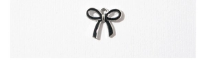 Close-up of black enamel bow pendant with silver edges for DIY jewelry making