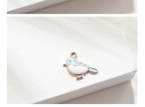 Close-up of a gold-plated bird charm with blue and white enamel for DIY jewelry