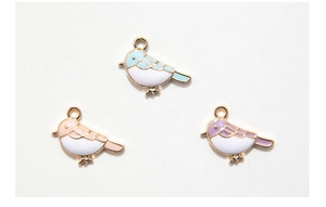 Detailed view of three colorful enamel bird pendants in blue pink and purple for DIY jewelry