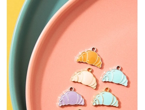 Macro shot of colorful enamel croissant charms in a tray for DIY jewelry making