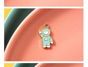 Close-up of blue and white enamel astronaut pendant with a golden metal finish and loop