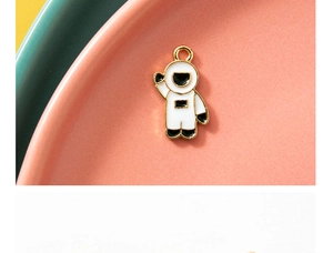 Macro view of cartoon astronaut enamel pendant with gold-plated metal edges for DIY jewelry