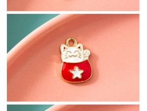 Vue macro d'un pendentif chat de la chance en émail rouge et blanc avec anneau doré