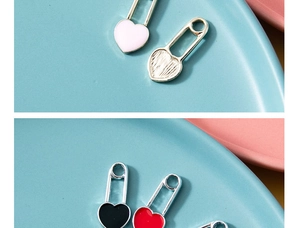 Macro shot of heart-shaped safety pin pendants in various enamel colors on ceramic plates