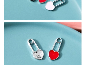 Macro shot of heart-shaped paperclip pendants in red and white enamel on a blue tray
