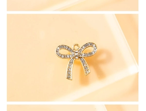Detalle de colgante de lazo bañado en oro con cristales blancos y anilla para joyería DIY