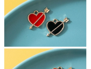 Detail van hart en pijl emaille bedeltjes in rood en zwart voor DIY sieraden