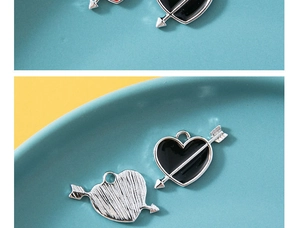 Macro detail van Cupido hart hanger met zwart emaille voorzijde en geborstelde achterzijde