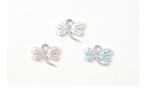 Close-up of three dragonfly alloy charms in white pink and blue for DIY jewelry making