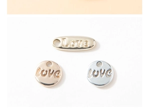 Vue macro de trois pendentifs Love en or, or rose et argent pour bijoux DIY créatifs