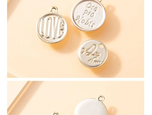 Macro detail of round silver pendants with Love and Ora pro Nobis embossed inscriptions