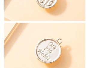 Detailed macro view of silver alloy disc pendant with Ora Pro Nobis embossed lettering