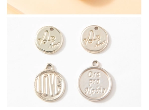 Detail of four engraved gold-tone alloy circular pendants for DIY jewelry making