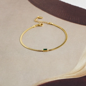 Detail eines Gold-Schlangenarmbands mit smaragdgrünem Zirkon und verstellbarem Verschluss