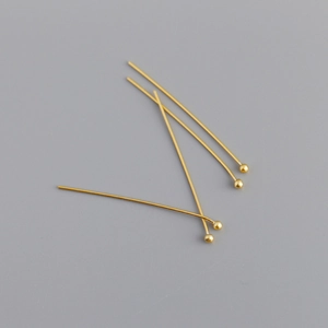 Detailed view of five polished gold-plated ball head pins for DIY jewelry making