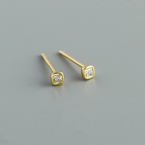 Macro shot of square princess cut zircon stud earrings in a polished gold finish