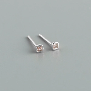 Macro shot of minimalist square silver earrings featuring small pink cubic zirconia stones