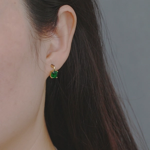 Detail of s925 silver gold-plated stud earrings with square-cut green zircon on model