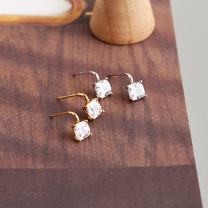 Detail showing classic square-cut cubic zirconia stud earrings in gold and silver finish