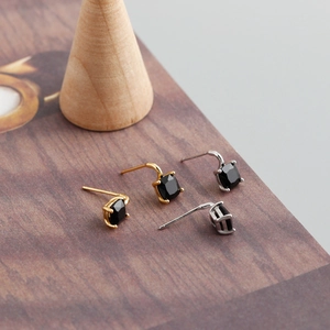 Macro shot of S925 sterling silver hallmark and square black zircon studs on wood base