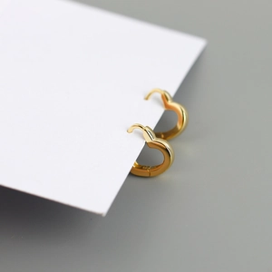 Macro shot of gold heart hoop earrings in s925 silver on a white jewelry display card